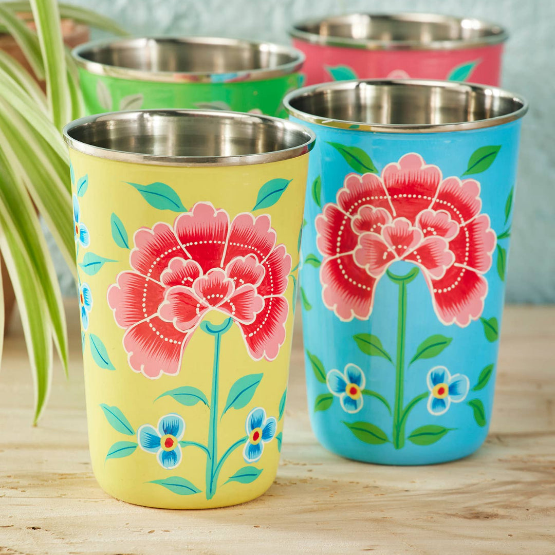 Set of colourful tumblers with floral designs on a wooden surface.
