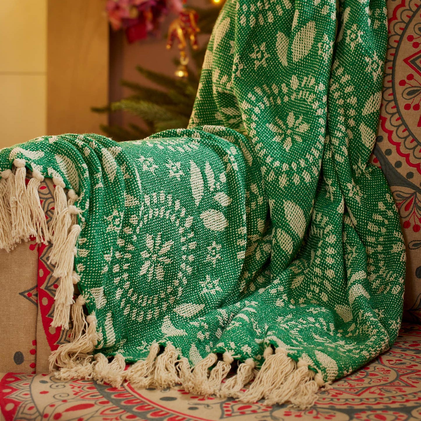 Green patterned blanket with white fringe on a decorative background