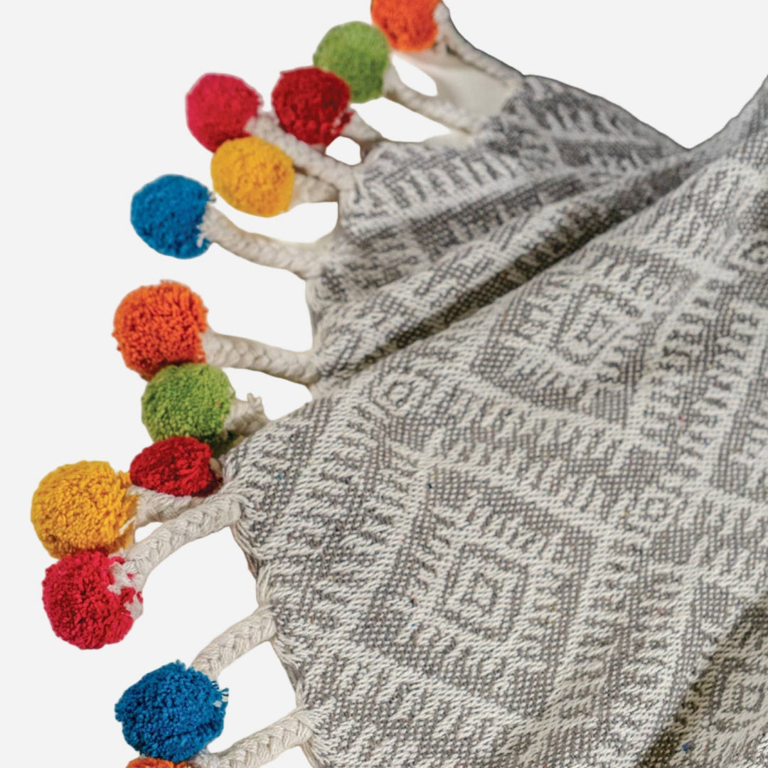 Grey textured blanket with colourful pom-pom trim