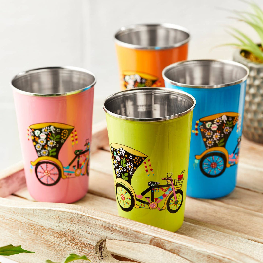 Set of colorful, hand painted stainless steel tumblers with bicycle designs on a wooden surface.