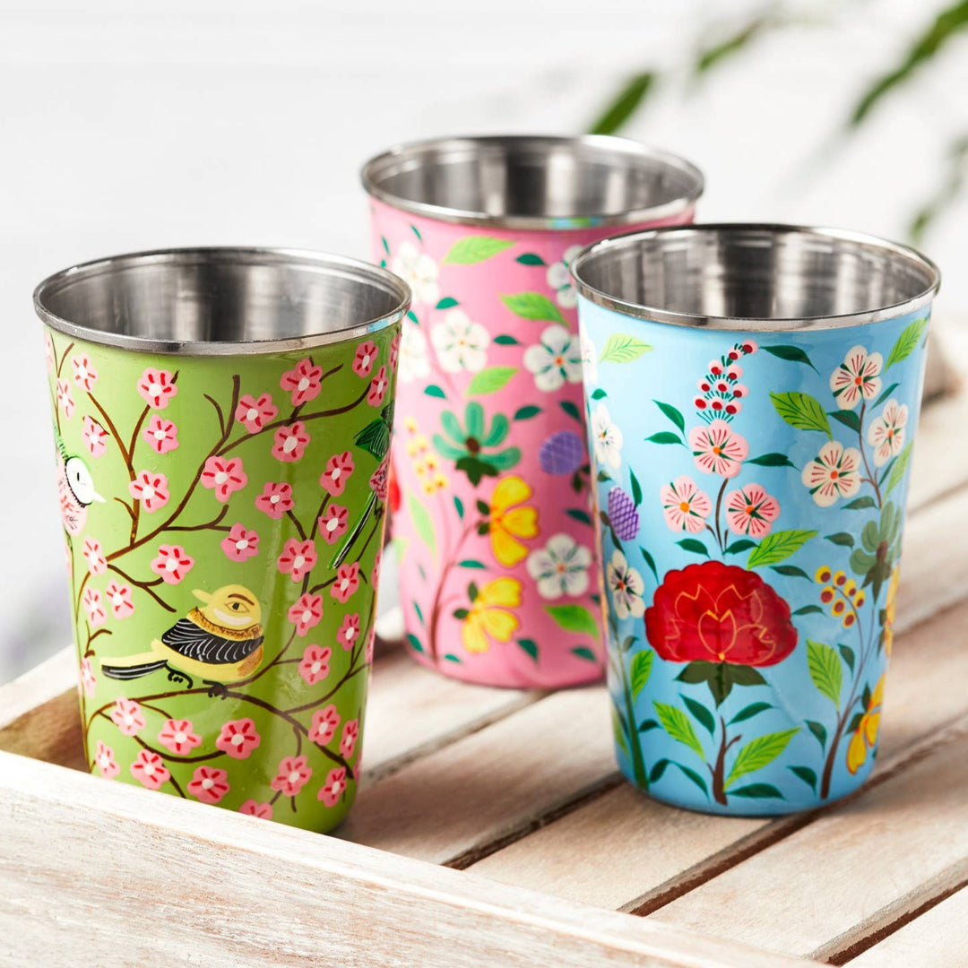 three beautifully hand painted enamel tumbler, one green with pink flowers, one light blue with white, pink and yellow flowers, one pink with white and yellow flowers.
