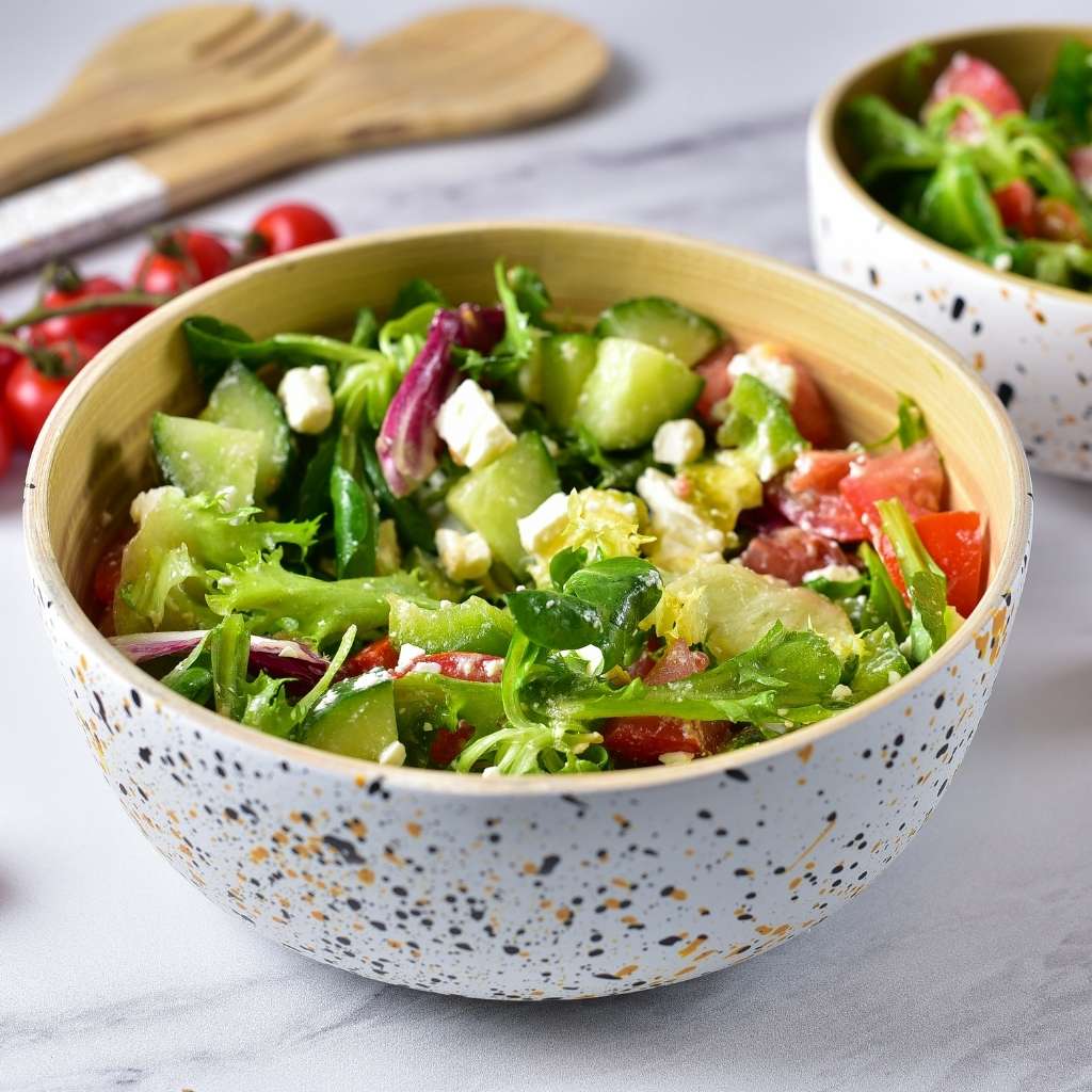 Bowl of fresh salad with vegetables on a marble surface