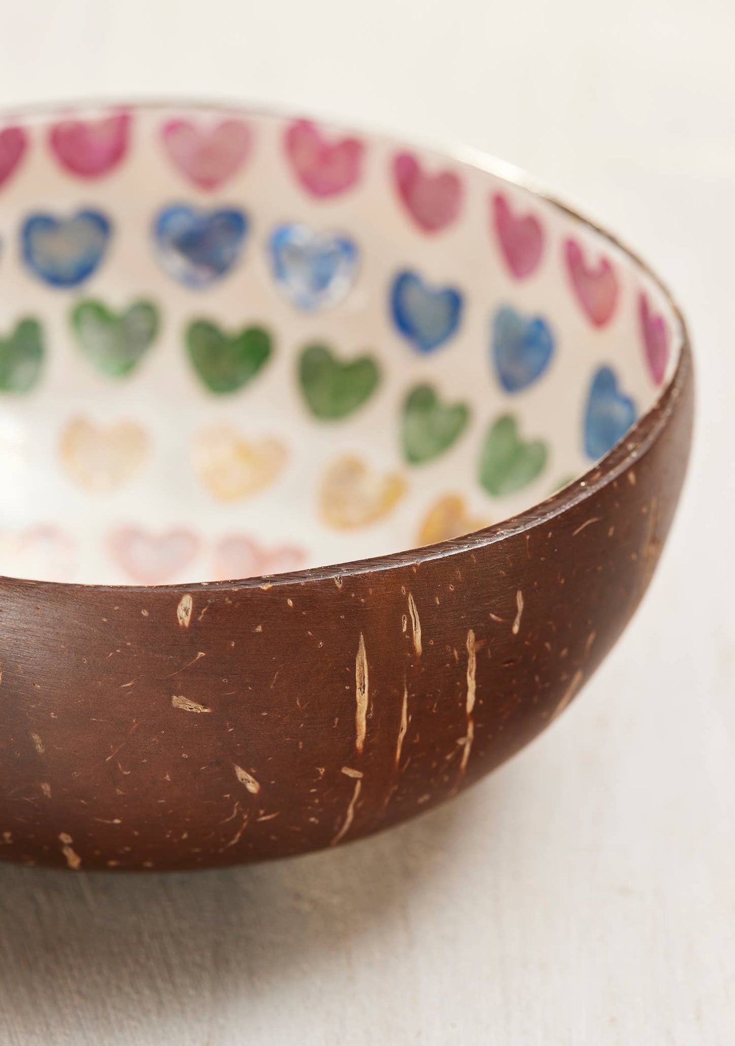 Coconut bowl with a colorful heart pattern inside on a light background