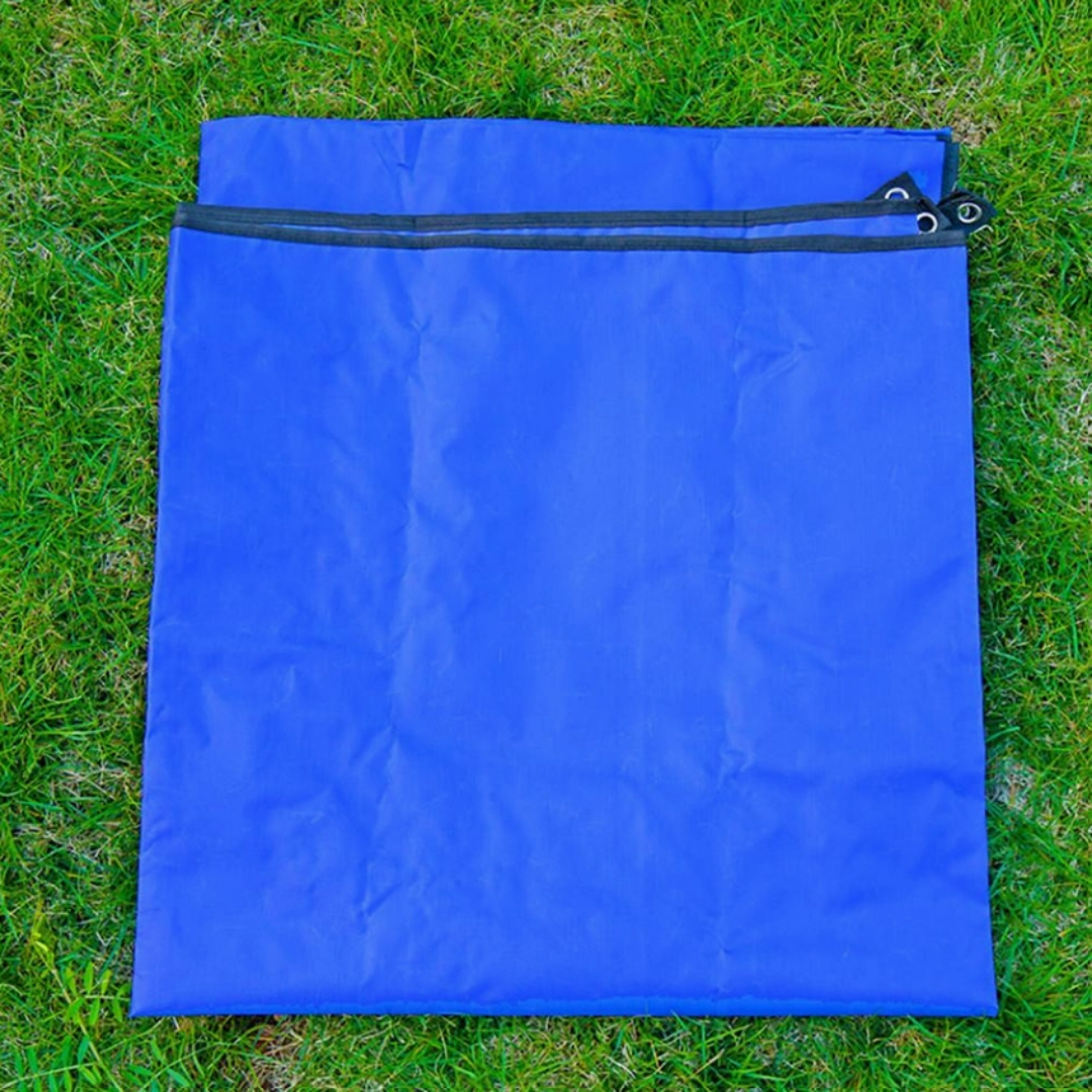 folded blue waterproof picnic blanket or groundsheet on flat green grass background