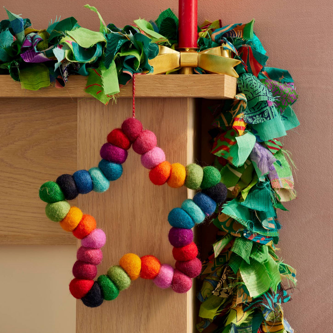 Decorative star wreath with colourful pompoms and a red hanging string