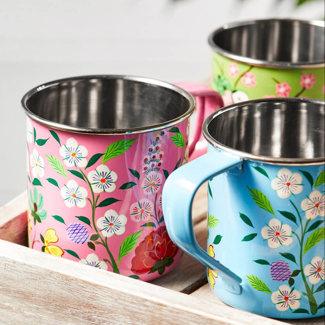 Three floral-patterned mugs on a wooden tray with a blurred background