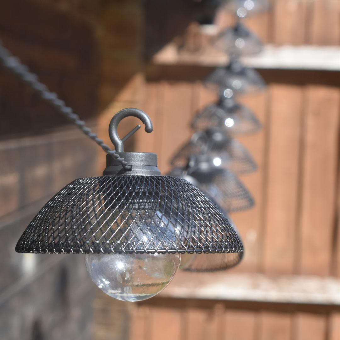 solar powered mesh lantern black string lights shown against brown garden fence