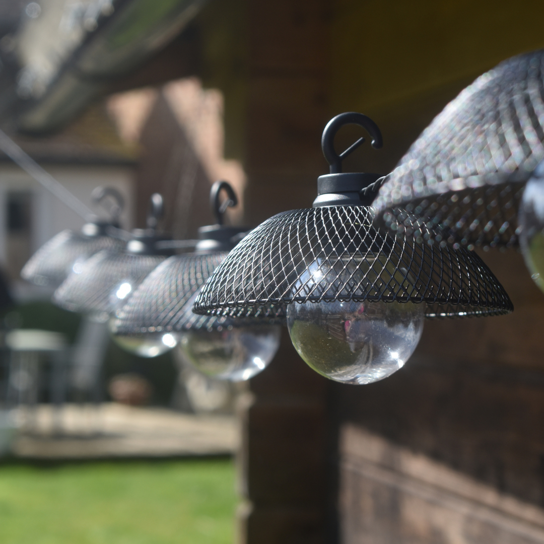 solar powered mesh lantern string lights with large round bulbs shown against garden shed