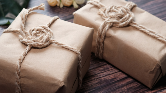 two brown paper parcels tied with natural string on a wood background