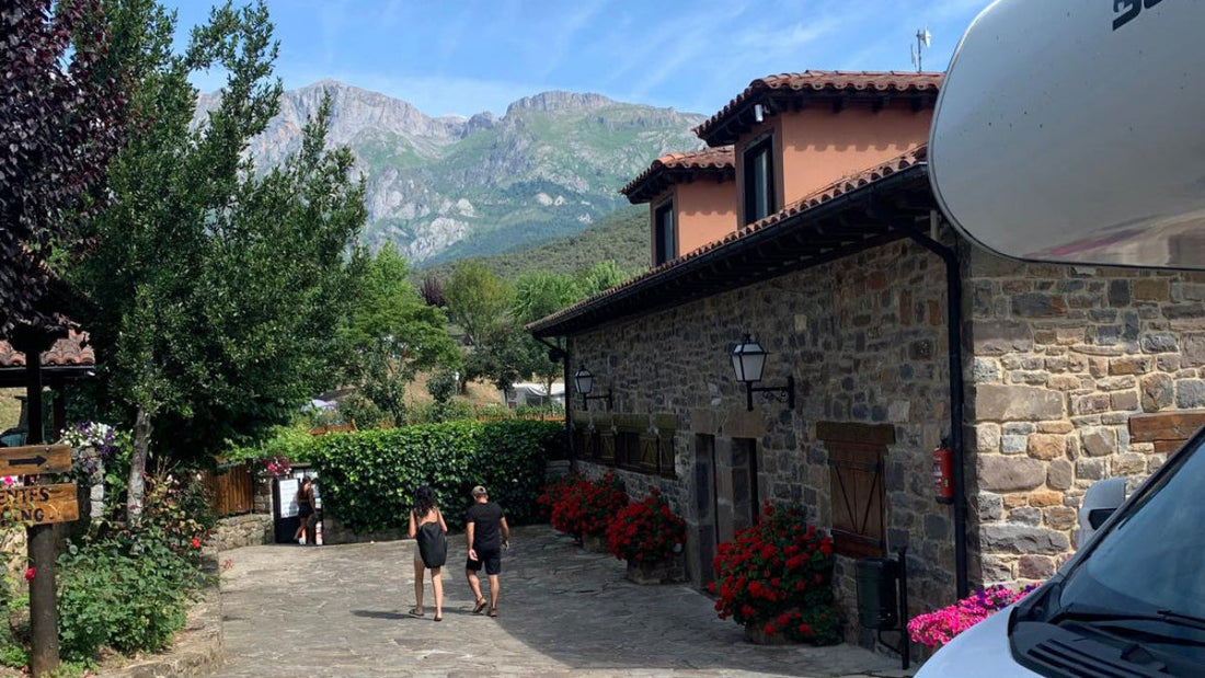 sunny campsite in Potes Spain with stone building and mountainous backdrop