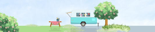Blue and white caravan on a sky blue background with camping table and wine bucket.