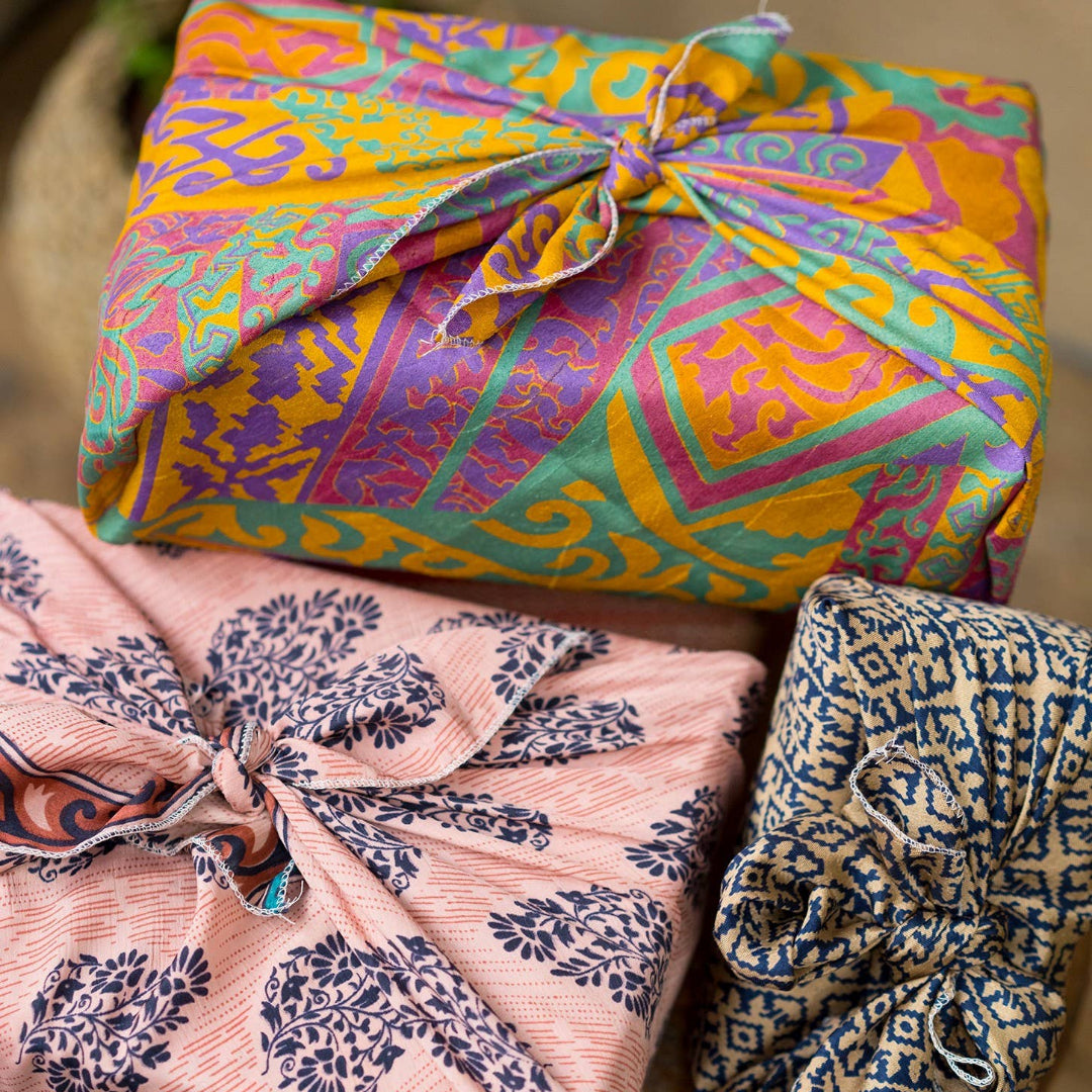 Three wrapped packages with colorful patterns on a rustic surface