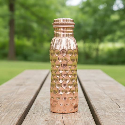 Copper water bottle with honeycomb pattern on a light grey background