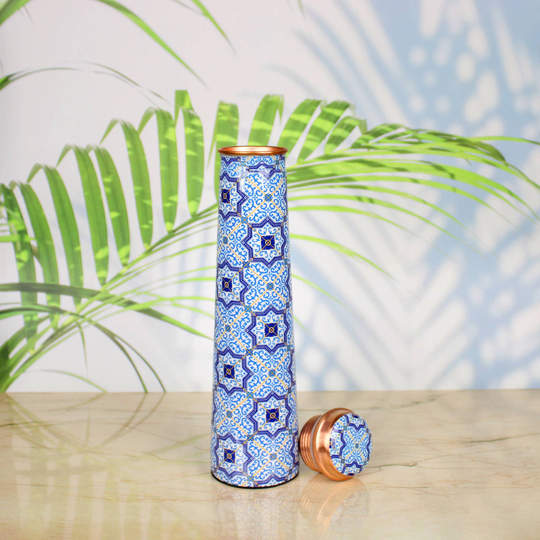 Decorative water bottle with blue mosaic pattern on a wooden surface with a natural background