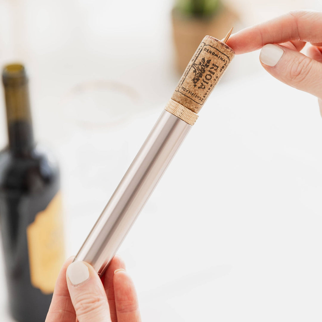 Person holding a wine bottle corkscrew and cork blurred background