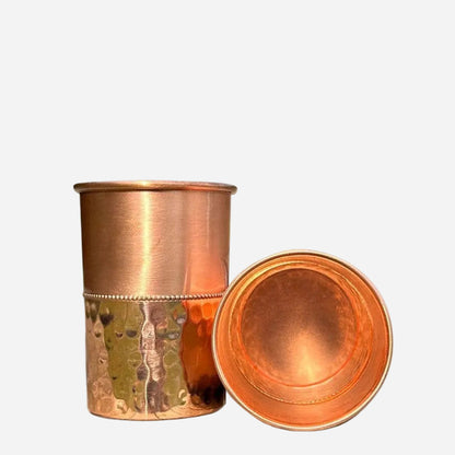 Two copper cups, one upright, one on side with a view of inside, on a white background