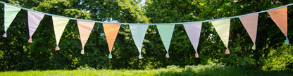 pastel triangular flags hanging on a string against a green outdoor background