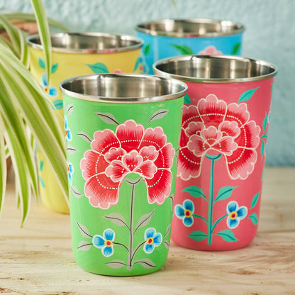 Set of four colourful tumblers with floral designs on a wooden surface.