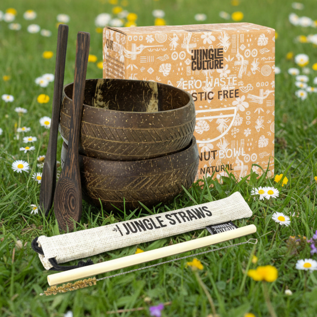 Set of coconut bowls with wooden spoons and straws from The Jungle Culture on a spring field background.