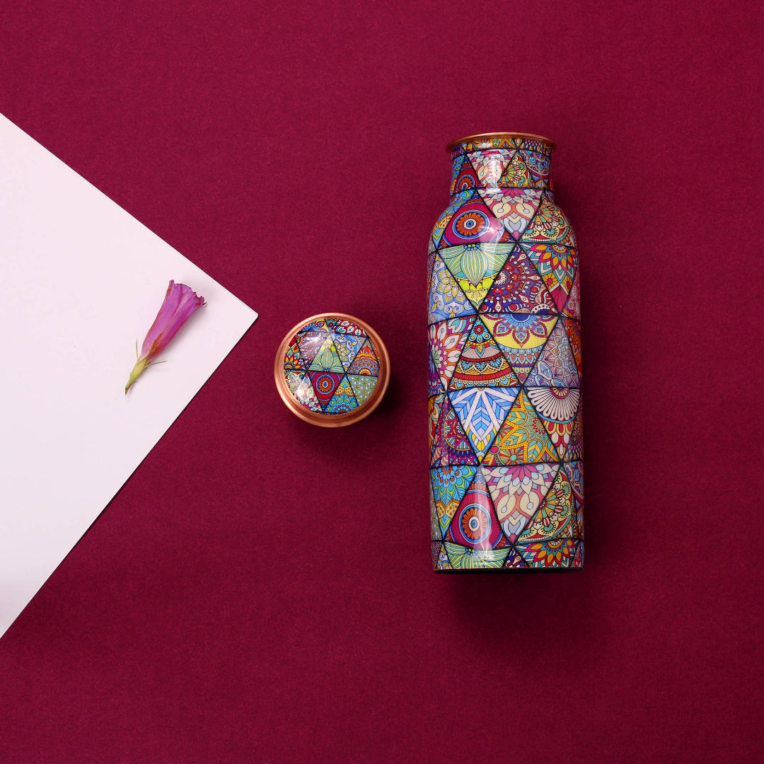 Colorful geometric-patterned copper bottle and lid on a maroon background