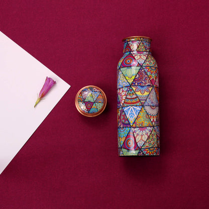 Colorful geometric-patterned copper bottle and lid on a maroon background