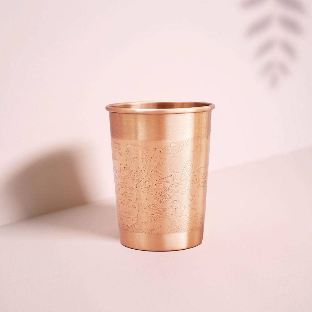 Bronze cup with embossed design on a light pink background