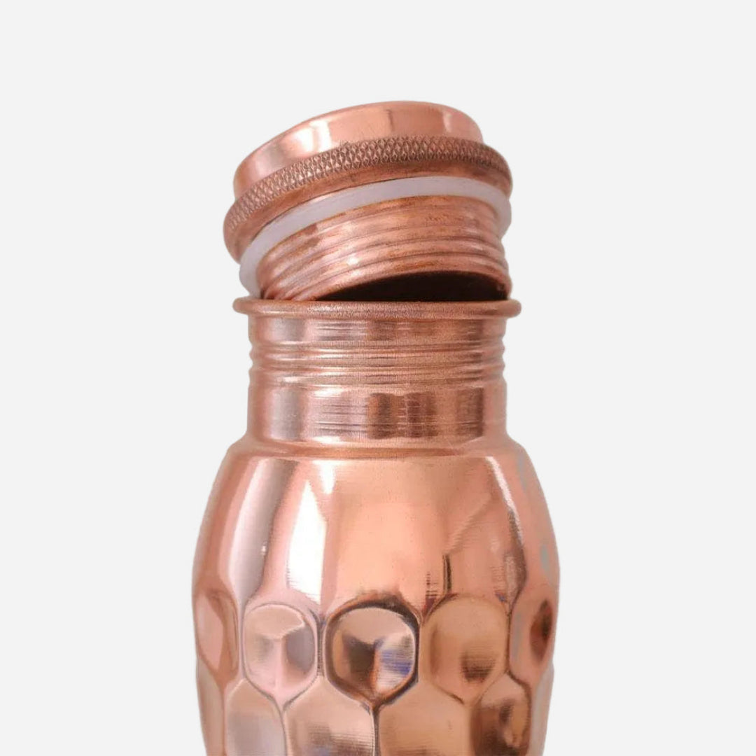 Copper water bottle with textured design on a light grey background