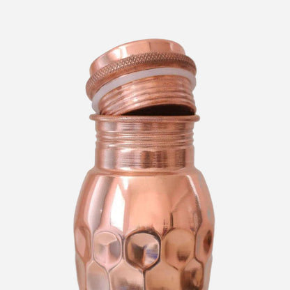 Copper water bottle with textured design on a light grey background