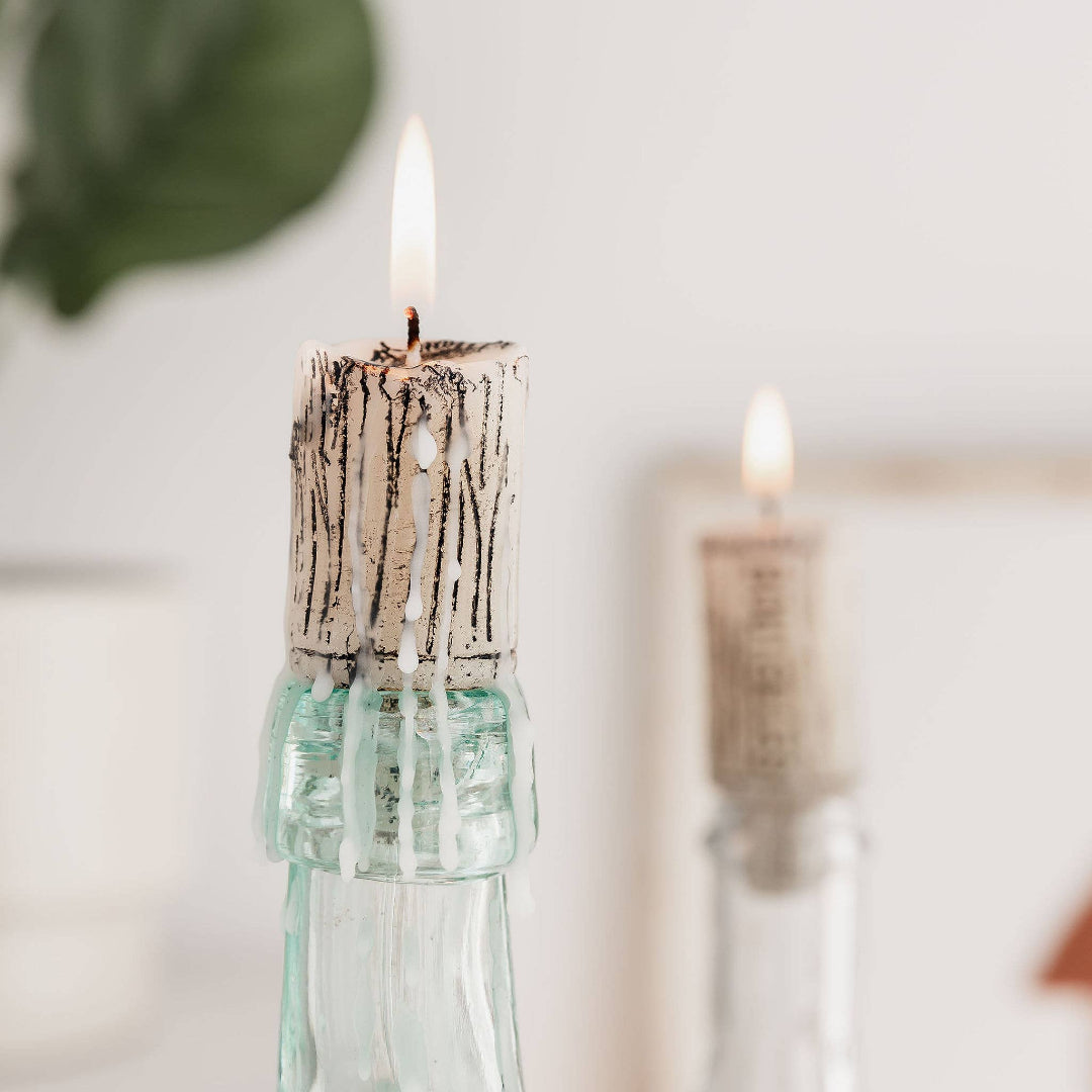 two cork-shaped candles inside empty wine bottles
