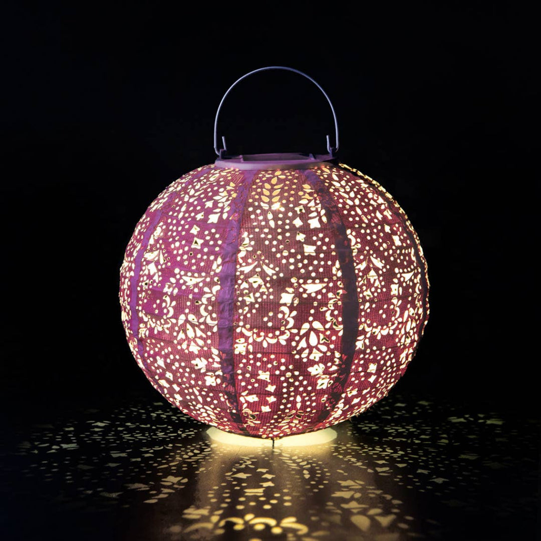Decorative lantern with intricate cut-out patterns on a dark background
