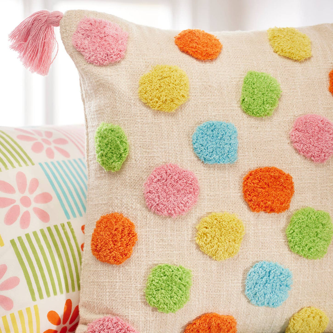 Decorative pillow with colorful pom-poms on a floral-patterned couch.