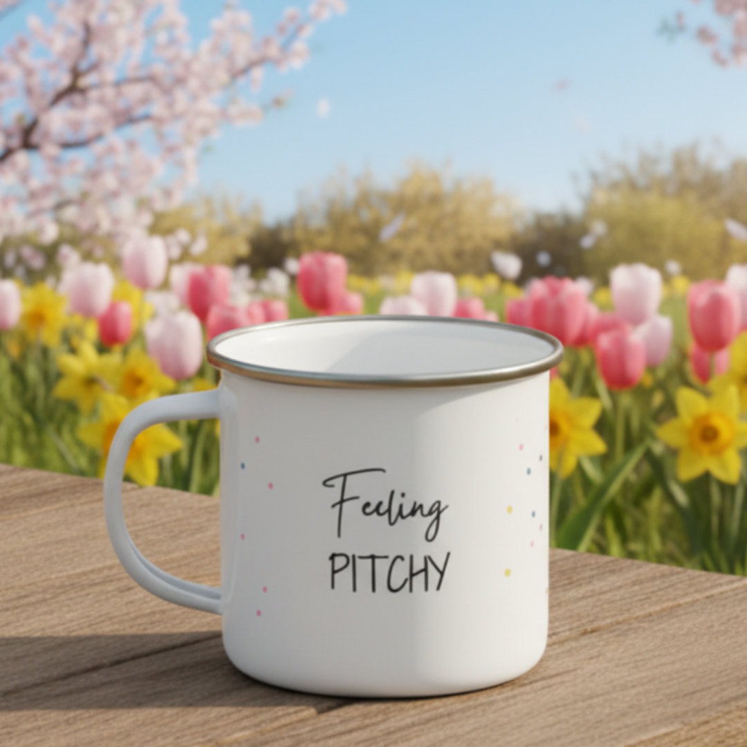 White mug with 'Feeling Pitchy' text on a wooden surface with a floral background