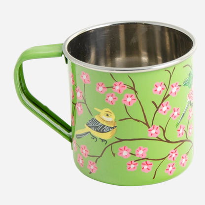 Green mug with floral design and bird illustration on a light grey background