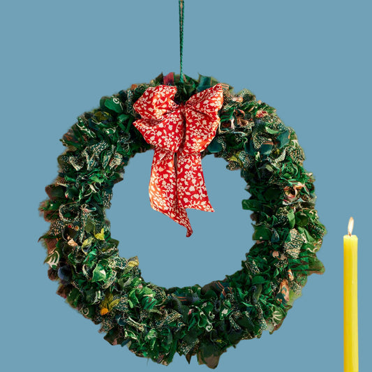 Decorative wreath with a red bow on a blue background with a yellow candle