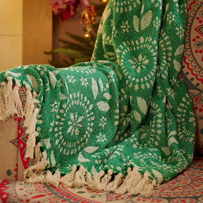Green patterned blanket with white fringe on a decorative background