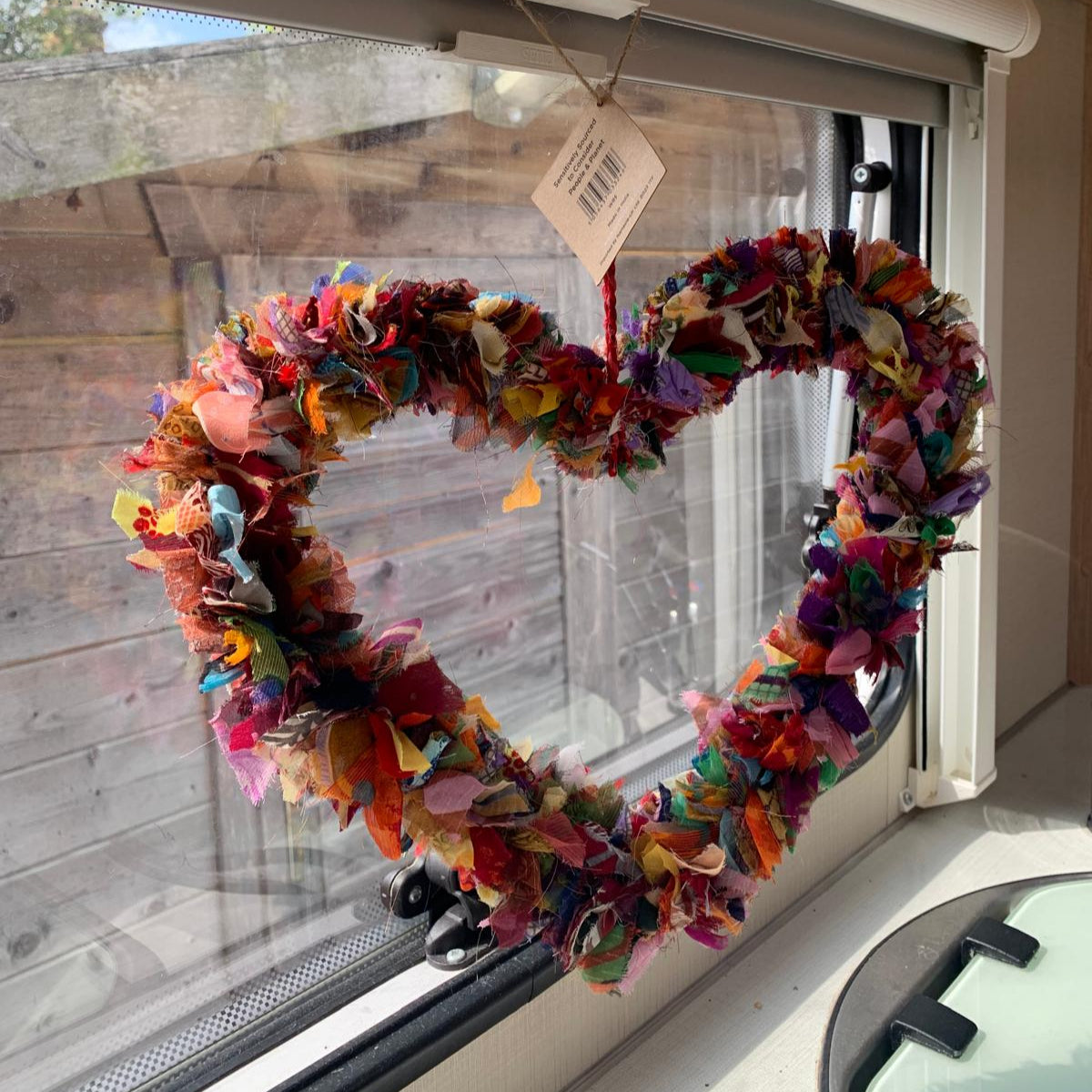 Colorful fabric heart-shaped wreath hanging on a campervan window