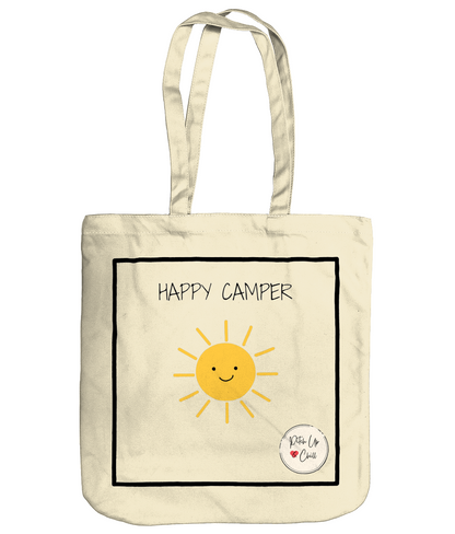 Natural tote shopping bag with large black square, yellow smiling sunshine and text "happy camper" above the sun. Pitch Up and Chill logo bottom right corner.