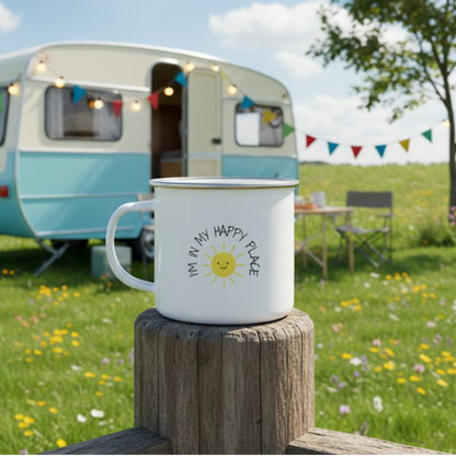 A white enamel mug with a handle, featuring a graphic of a sun and text that reads 'I'M IN MY HAPPY PLACE'.
