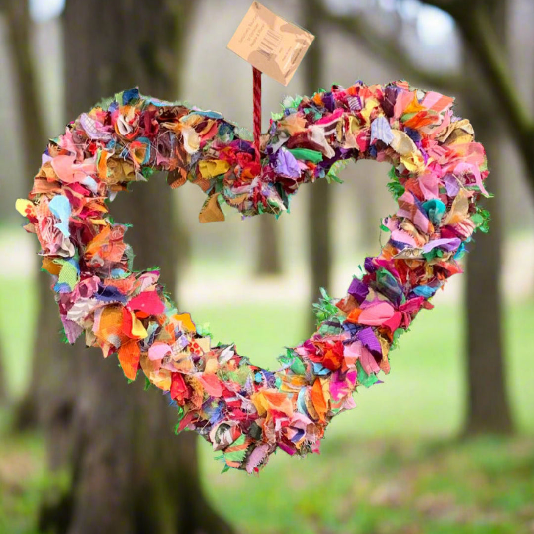 Colorful fabric heart-shaped wreath made from recycled sari offcuts within a woodland setting