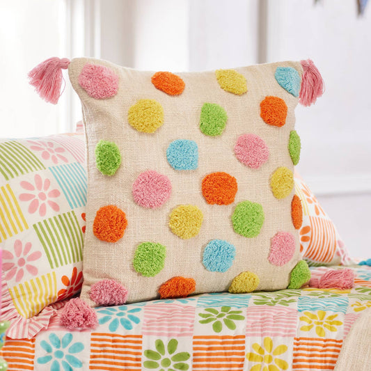Colorful polka dot pillow with pink tassles on a floral bedspread