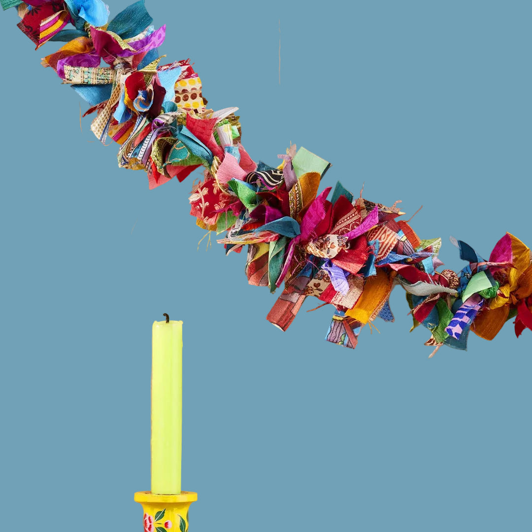 Decorative colorful fabric garland, yellow candlestick with floral design.
