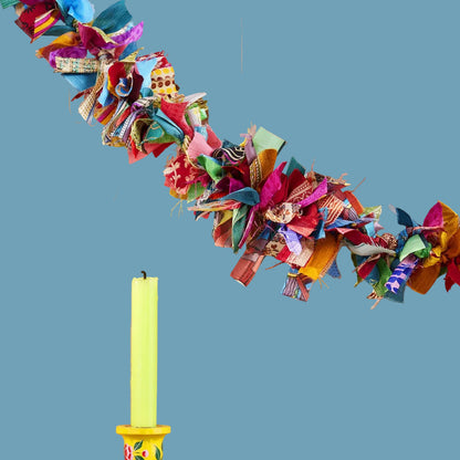 Decorative colorful fabric garland, yellow candlestick with floral design.