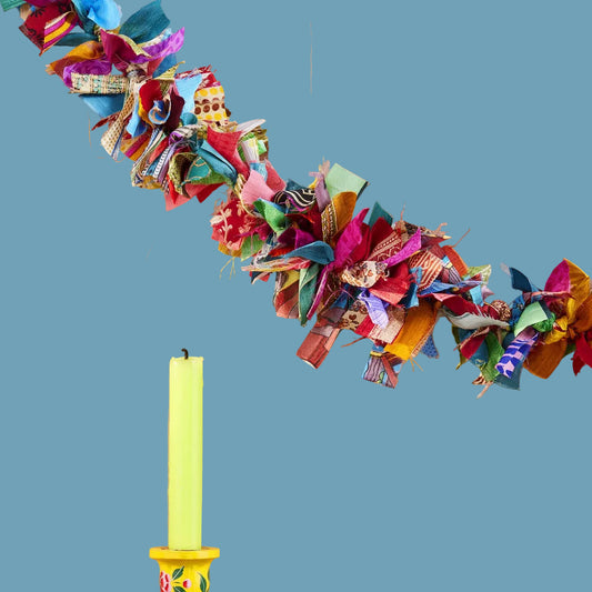Decorative colorful fabric garland, yellow candlestick with floral design.