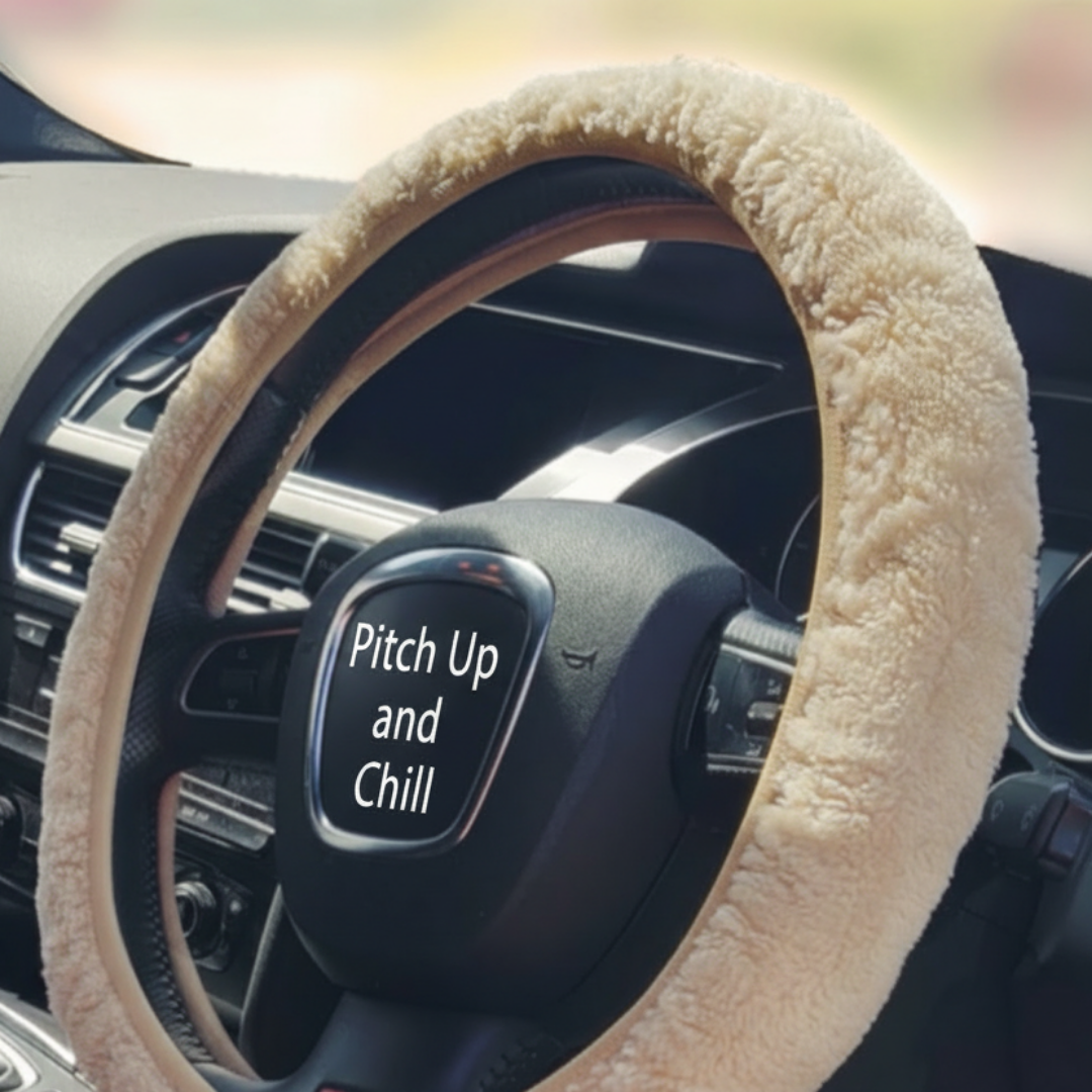 Car interior with a steering wheel covered by a beige sheepskin steering wheel cover.