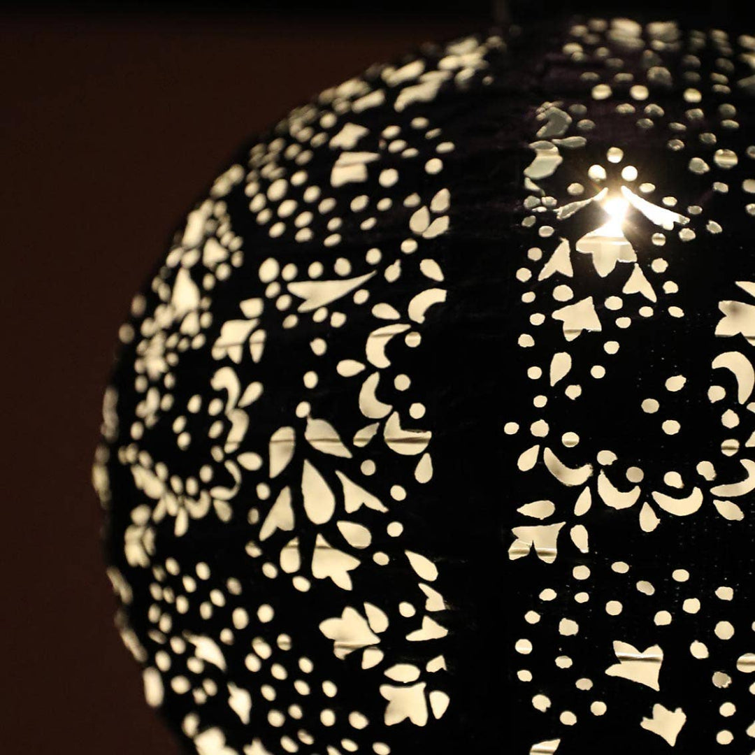 Decorative solar lantern with intricate cut-out design on a dark background
