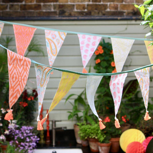 Colourful fabric bunting with tassels against a garden backdrop