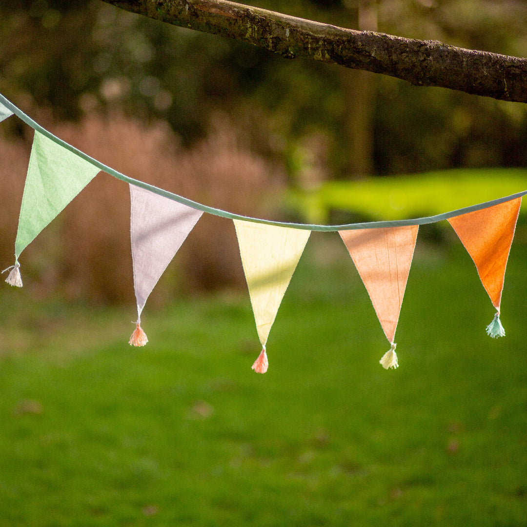 Colorful pastel pennant flags hanging on a string against a natural background