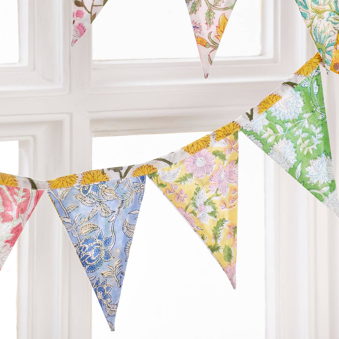 Colorful floral fabric bunting hanging against a white window frame.