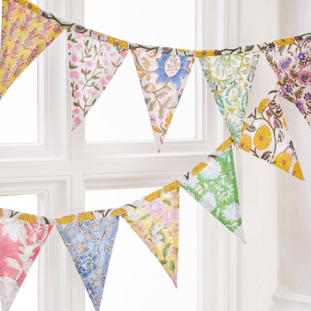 Floral patterned bunting hanging against a white window.