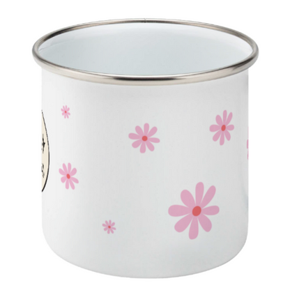 white enamel mug with pink daisy flowers of varying sizes against a light grey background.